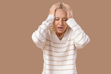 Mature woman having panic attack on beige background
