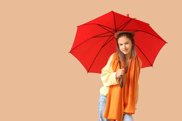 Cute teenage girl with red umbrella on brown background