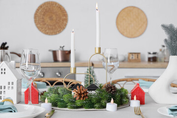 Beautiful festive table setting for Christmas celebration with wreath and candles in dining room