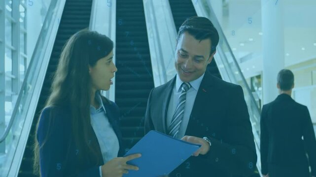 Business professionals unfolding documents and explaining escalator layout in lobby