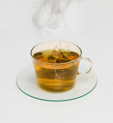 Hot herbal camomile tea in glass teacup with steam floating above