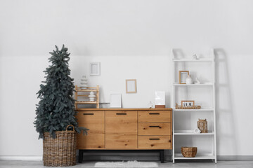 Interior of living room with Christmas tree, commode and shelf unit