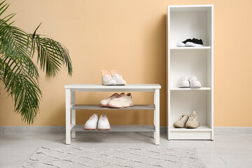 Sneakers with orthopedic insoles on bench near beige wall in hallway