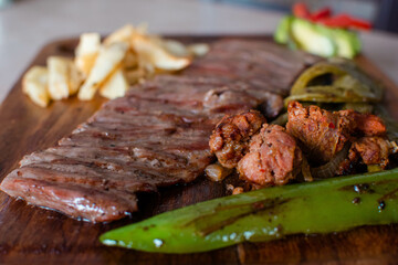 Plano a detalle de una carne asada con longaniza, nopales, y papas fritas