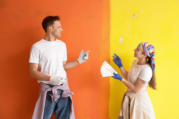 Young couple with color palettes painting wall in room