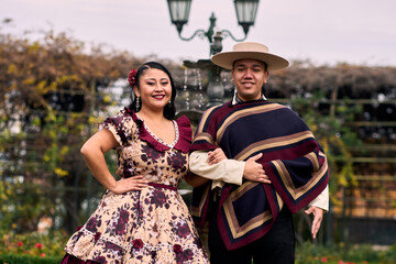 Portrait of a smiling young couple, dressed as Chilean huasos, posing romantically to dance cueca,...