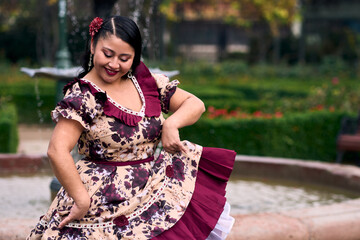 Portrait of a beautiful, smiling young woman, happily dressed in a Chilean huasa, celebrating,...