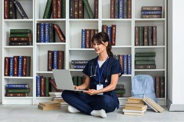 Female medical intern studying with laptop in library