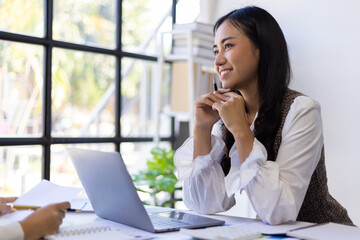Colleagues talking in the office. Two Asian female employees are discussing work together.
