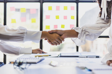 Asian woman shaking hands with coworker in workplace. Businesswoman shaking hands with business partner in the office.