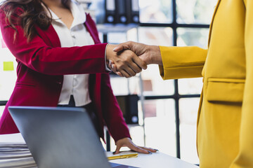 Asian woman shaking hands with coworker in workplace. Businesswoman shaking hands with business partner in the office.
