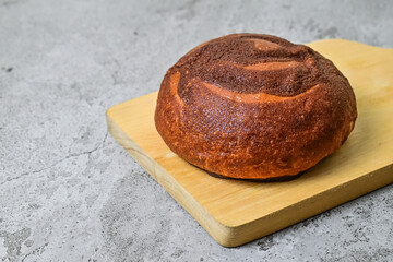 Close up view of coffee bun on wooden cutting board. grey or gray cement on background. bread home...