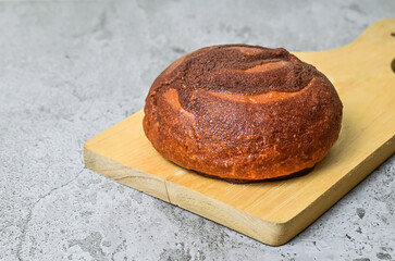 Close up view of coffee bun on wooden cutting board. grey or gray cement on background. bread home made. Mexican Coffee Bun.