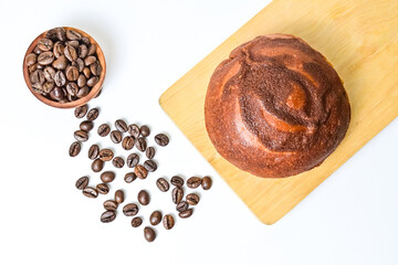 Top view of coffee bun on wooden cutting board with roasted coffee beans in the little wooden bowl isolated on white background. Coffee bun bread home made. Mexican Coffee Bun. clipping path, above.