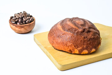 Close up view of coffee bun on wooden cutting board with roasted coffee beans in the little wooden bowl isolated on white background. Coffee bun bread home made. Mexican Coffee Bun. clipping path.