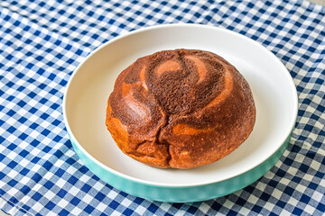 Close up view of coffee bun on plate isolated on napkin background. blue, white. bread home made. Mexican Coffee Bun.