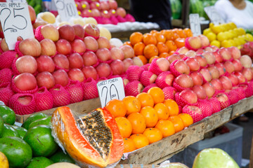 Apples, oranges, papaya, and avocados displayed at tropical fruit market stall with price tags in Philippines