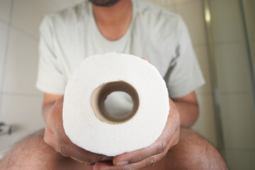 Person holding toilet paper in a bathroom setting