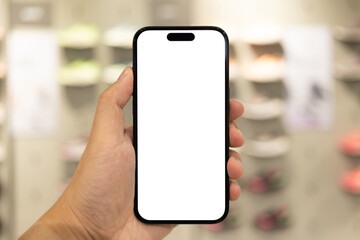 Hand Holding Blank Smartphone in Shoe Store. Mobile shopping for footwear, using retail apps,...