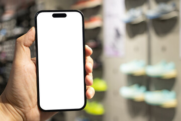 Hand Holding Blank Smartphone in Shoe Store. Mobile shopping for footwear, using retail apps,...