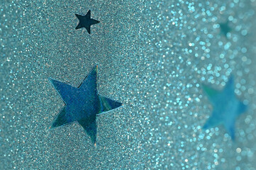 Close-up of teal glitter surface with star-shaped cutouts