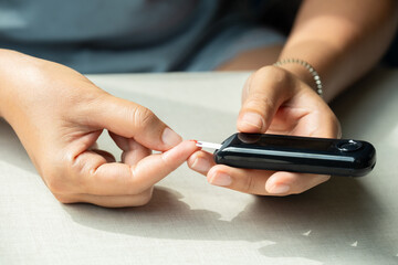 Woman's hands checking diabetes and hyperglycemia with digital blood sugar meter. Healthcare and...