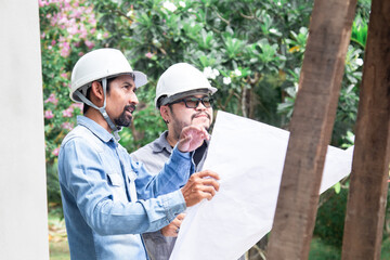 Team of Asian managers, foremen, or engineer construction supervisors wearing white helmet hold ...