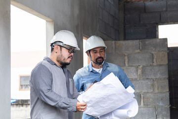 Team of Asian managers, foremen, or engineer construction supervisors wearing white helmet hold ...