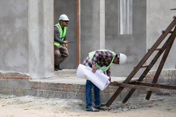 Two construction foreman workers examine inspect unfinished property site outdoor, Asian or Indian...