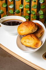 vertical photo of traditional handmade whole wheat mogolla bread next to a cup of coffee in a healthy vegetarian restaurant in Colombia