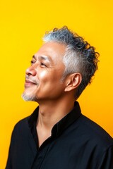 Idea visual artwork of style for aging men. Yellow solid background. A modern and graceful man smiling naturally. Fashionable men's fade haircut - midlife southeast asian man with curly hair.