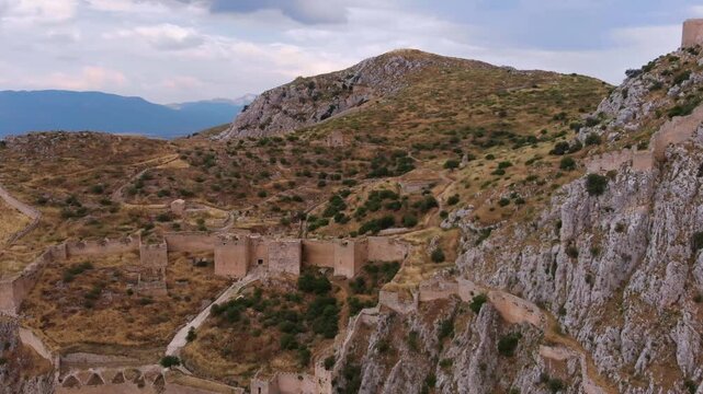 Panoramic aerial drone footage showcasing the historic medieval castle of Acrocorinth, an ancient citadel perched atop a hill overlooking the ancient city of Corinth in Greece, with breathtaking views