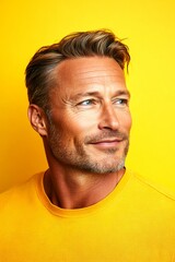 A fashionable man posing for a stylish portrait. Fashionable men's side part haircut - midlife white man with blond hair. Yellow solid background. Idea concept art of style for aging men.