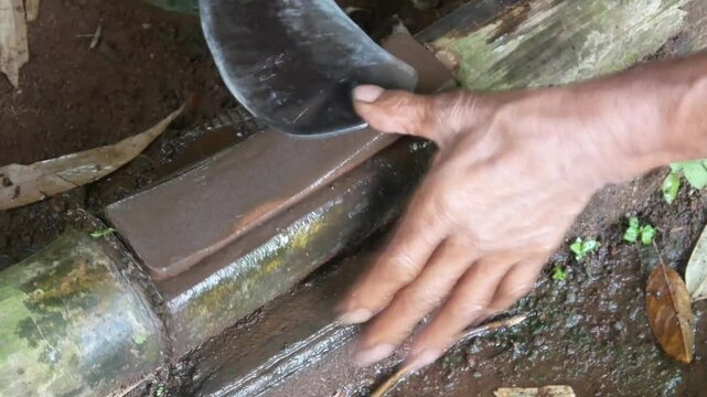 a man's hand sharpening a machete on a sharpening stone