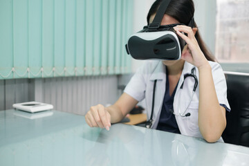 Asian female doctor in the office using VR simulation for training and treating patients with...