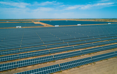 Expansive solar panel arrays under a clear blue sky in a vast renewable energy farm