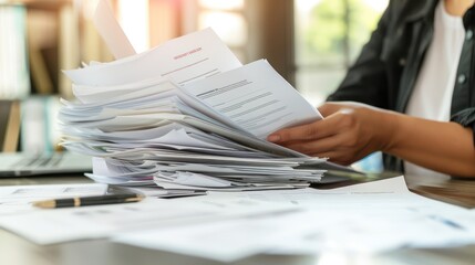 HR professional reviewing a stack of resumes and employment documents.