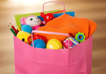 Obraz premium Pink paper bag filled with toys and clothes for children