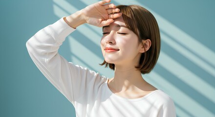 A woman in sunlight smiles gently with eyes closed and hand shielding her face.