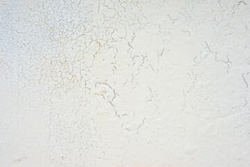White concrete wall exhibiting rough textured surface with cracks. Cracked concrete surface background texture. 