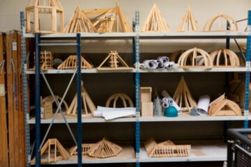 Flat design metal shelving unit is showing wooden architecture models in studio featuring teal hat