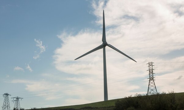 Fototapeta Windmill spinning over a green field