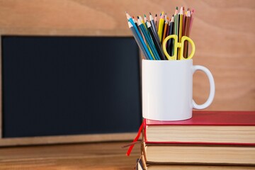 Desk organizer on stack of books against blackboard