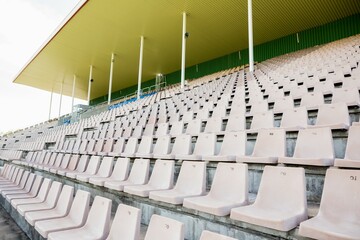 Flat design is featuring rows of empty beige plastic seats under yellow canopy with green columns