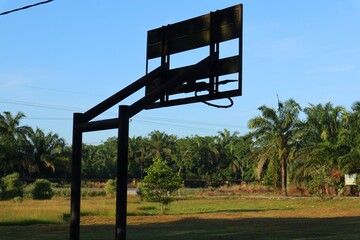 Silhouette of a basketball hoop standing alone in tropical landscape