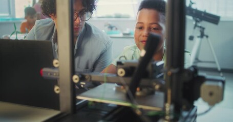 African American Elementary School Student Watching Printing Process on Automated 3D Printer on Programming Lesson. Teacher Educating Smart Young Boy in Modern Classroom. Interactive STEM Education. - Powered by Adobe