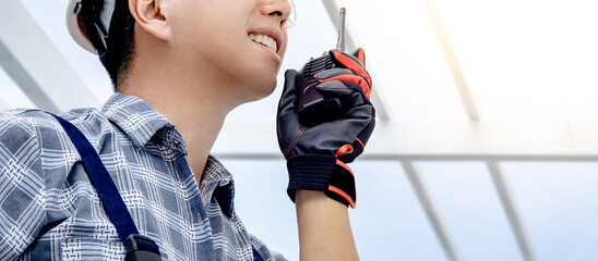 Half face of civil engineer man using walkie talkie to cooperate with the worker team while looking...