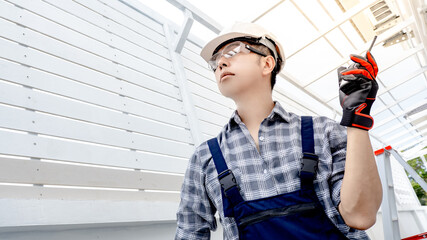 Asian man engineer holding walkie talkie using for cooperate with worker team while looking at...
