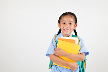 Portrait Asian smiling young girl kids kindergarten holding backpack and hugging books studio shot...