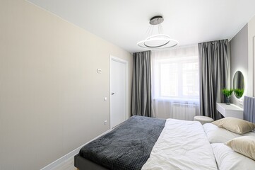 serene bedroom features a bed with gray velvet headboard, white linens, and a gray throw. Gray...